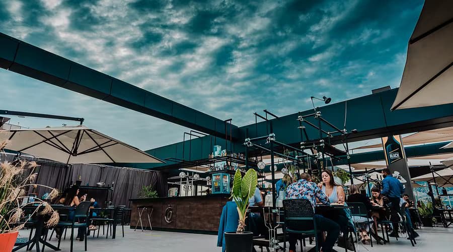 Espacio gastronómico exterior con barra, mobiliario y terminaciones.